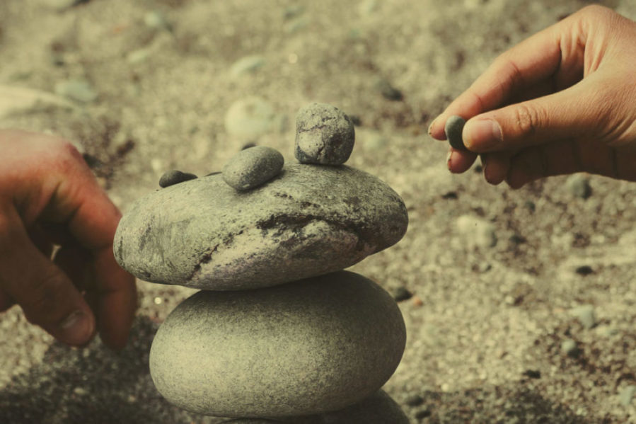 Händer bygger med stenar på strand - Lagotto